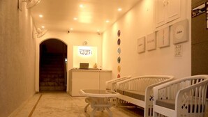 A reception area with a desk, chairs, and a wall with framed items. - Chakrah by Hermitage (Narendranagar)
