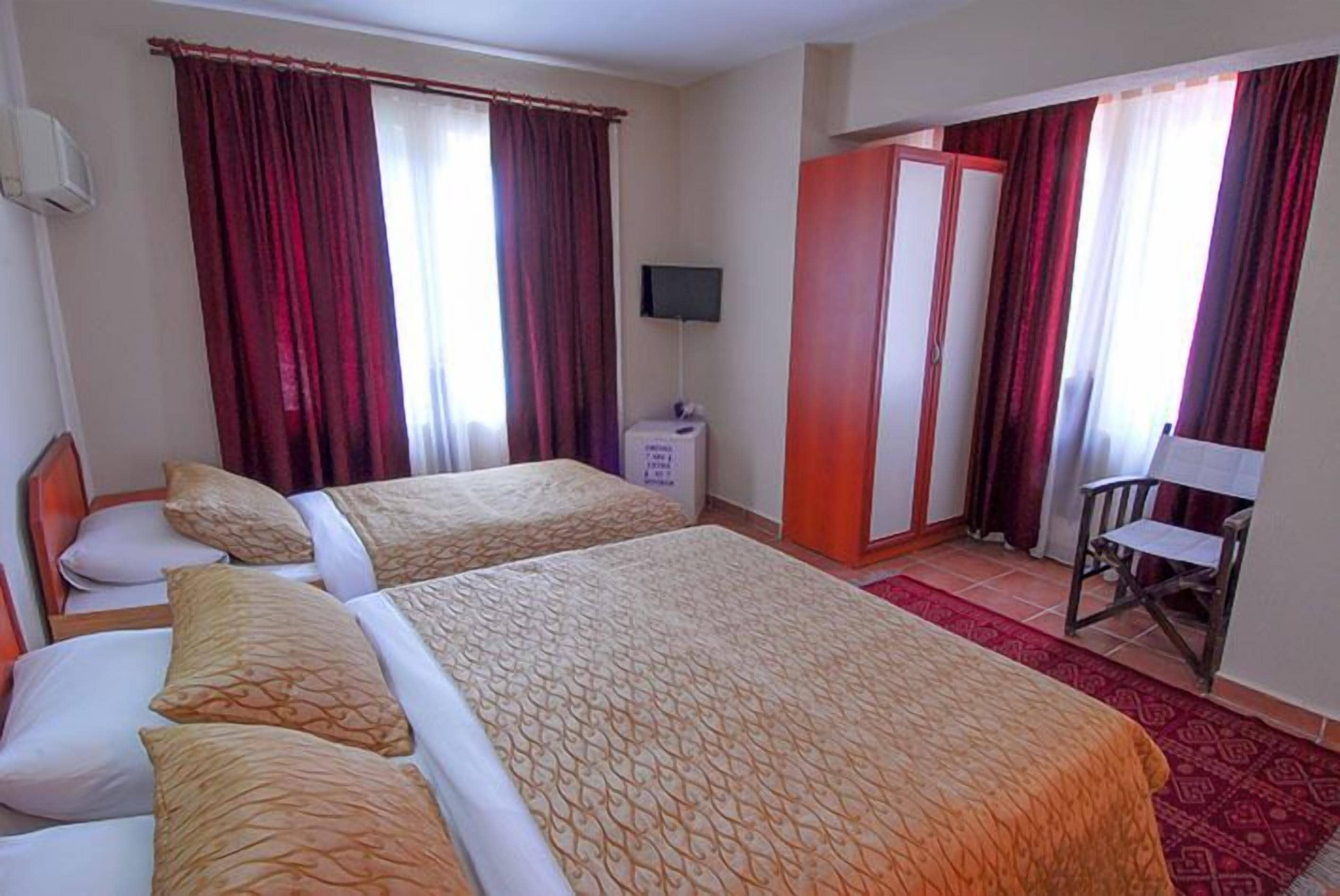 A hotel room with two beds, a TV, a wardrobe, and a desk with a chair.