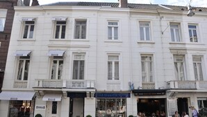 Un edificio blanco con varias fachadas comerciales, incluyendo un restaurante visible llamado 'Fred Stoelzie Brilla'.