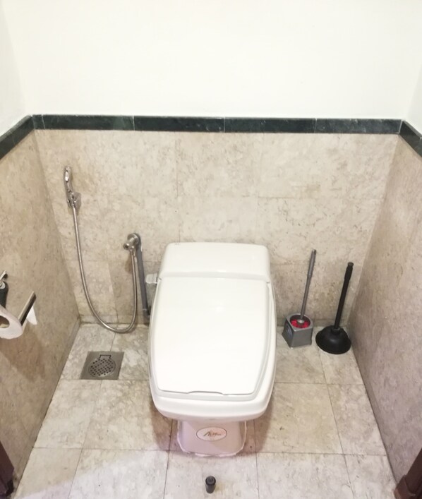 A bathroom with a toilet, a handheld showerhead, a bidet, and a plunger. - Golden Service Suite At Times Square (Kuala Lumpur)