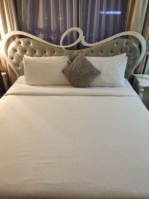 A neatly made bed with a tufted headboard, a patterned pillow, and a plain white pillow. - Golden Service Suite At Times Square (Kuala Lumpur)