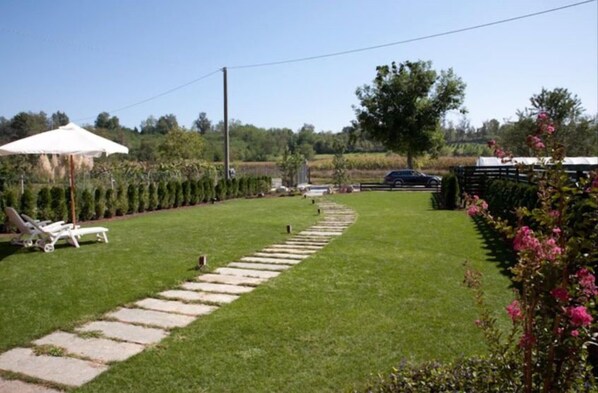 A well-maintained lawn with a stone pathway, a white umbrella, and a row of neatly trimmed bushes. - Il Torchio Snc (Pianfei)