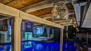 Habitació amb piscina, zona de bar i sostre amb bigues descobertes.