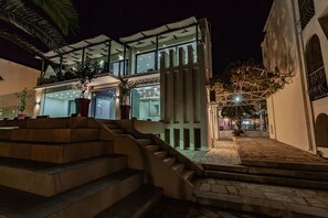 Ein modernes Gebäude mit Glasfassade, einer Treppe, die zu einer unteren Ebene führt, und einem mit Steinplatten bepflasterten Innenhof.