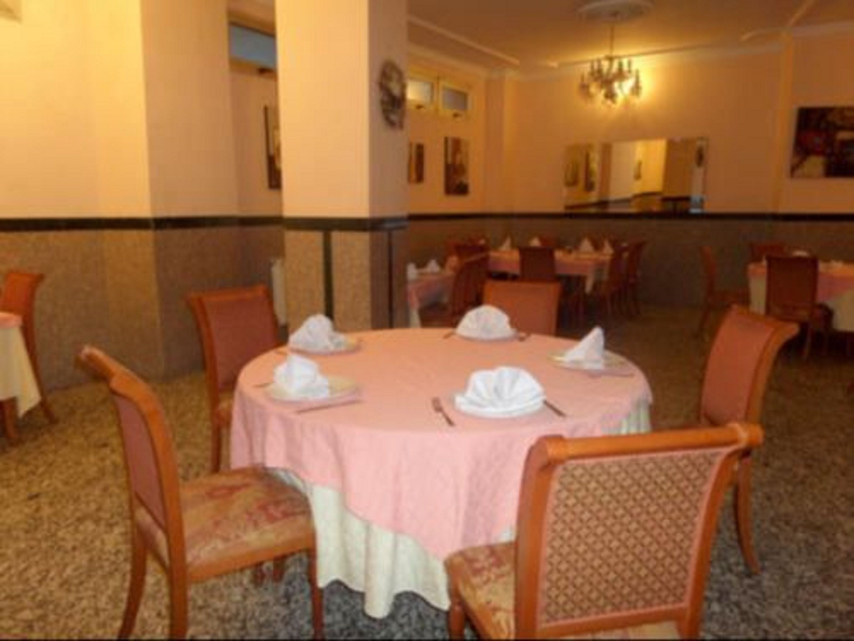 Un comedor con mesas redondas, sillas y una lámpara de araña.