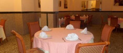 Un comedor con mesas redondas, sillas y una lámpara de araña.