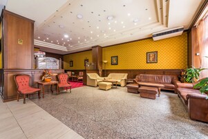 A lobby with a reception desk, seating area, and a wall-mounted air conditioner.