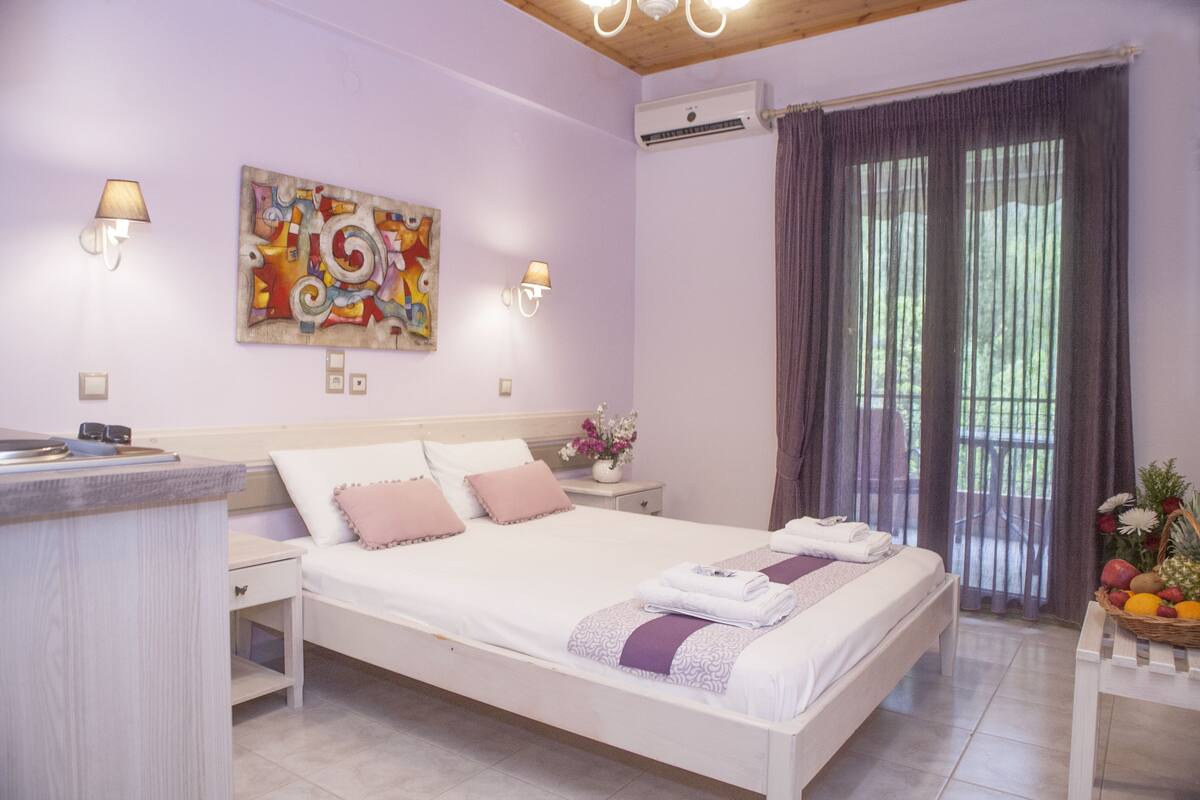 A bedroom with a bed, bedside tables, a wall-mounted artwork, and a window with curtains.