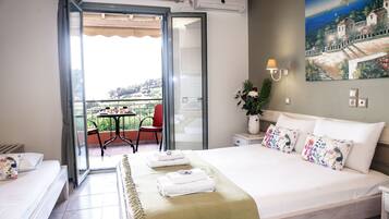 A hotel room with a bed, a balcony with a table and chairs, and a painting on the wall.