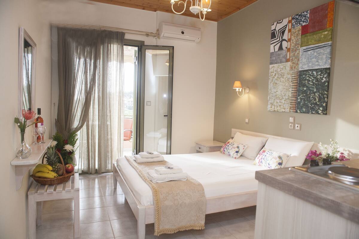 A hotel bedroom with a bed, bedside tables, a desk, and a view of the outside.