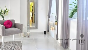 A modern living room with a grey sofa, a large mirror, and a view of the outdoors. - Unic Design Hotel (Playa del Carmen)