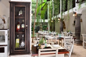 A restaurant with a dark wooden cabinet displaying liquor bottles, white chairs, and tables set for dining.