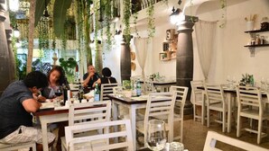 A restaurant with white chairs and tables, hanging plants, and a rustic interior. - Unic Design Hotel (Playa del Carmen)