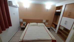 A bedroom with a bed, nightstands, a wardrobe, and a built-in shelf. - Hotel Diroma Fiore. (caldas novas)
