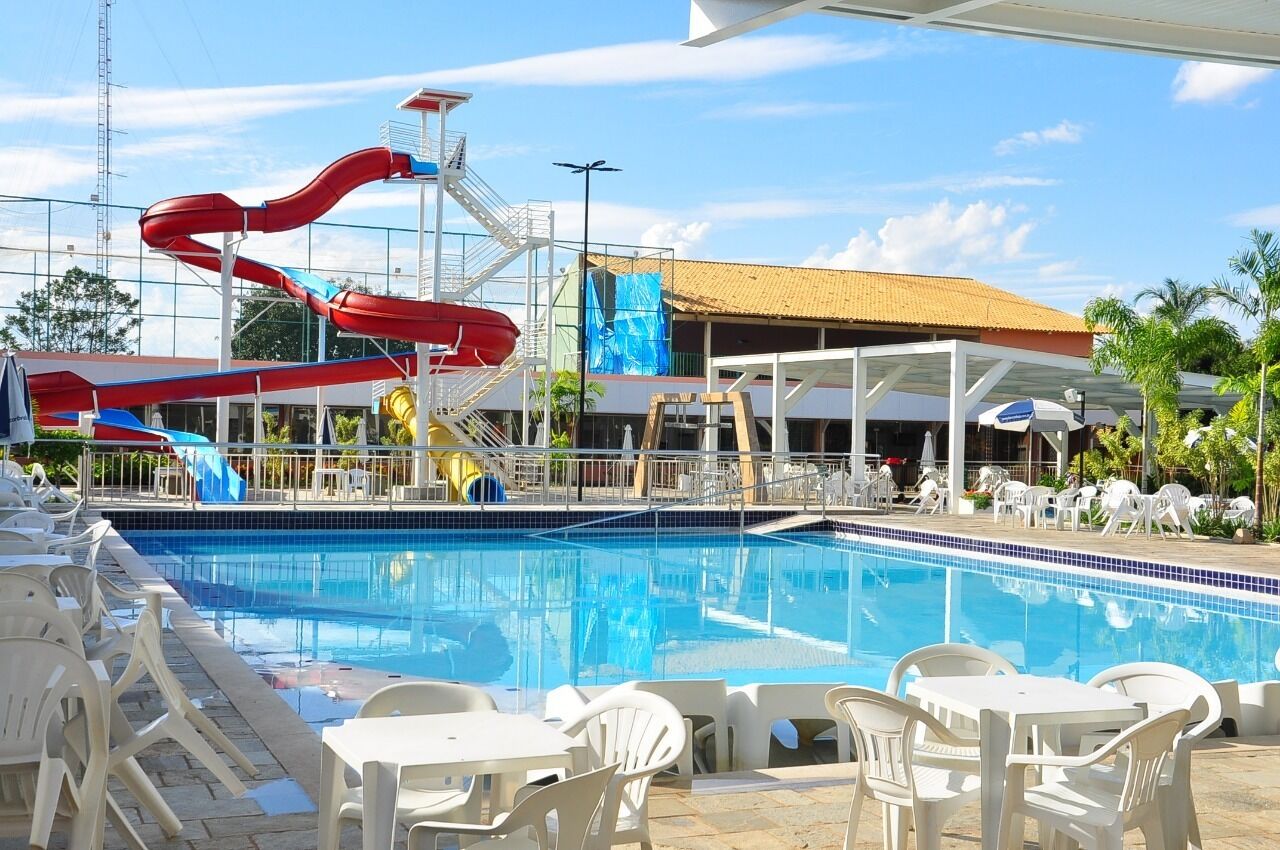A swimming pool with a water slide, lounge chairs, and a covered seating area.