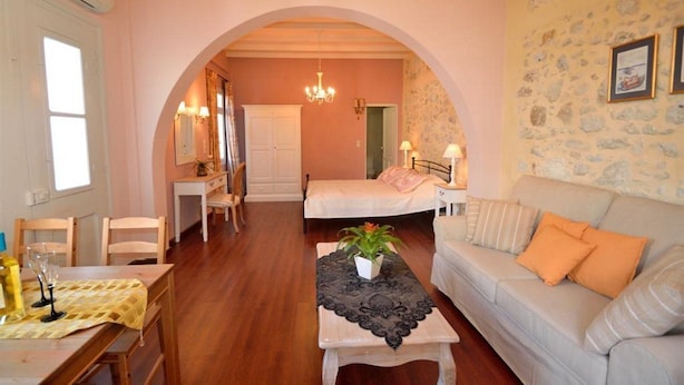 Una habitación acogedora con cama, sofá, mesa y una araña.