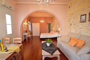 A cozy room with a bed, a sofa, a table, and a chandelier. - Lemon Tree House (Rethymno)