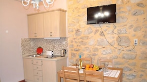Una cocina compacta con armarios de madera, una pared de piedra y un televisor de pantalla plana montado sobre la encimera.