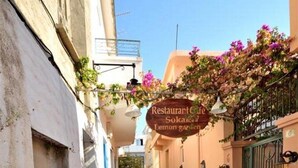 Una calle estrecha con un restaurante llamado 'Restaurant de Limon Garden' y una motocicleta estacionada a la derecha.