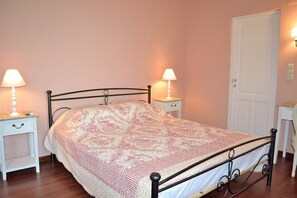 A bedroom with a bed, two bedside tables with lamps, a white door, and a small white table. - Lemon Tree House (Rethymno)