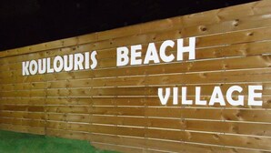 A wooden wall with the text "KOULOURIS BEACH VILLAGE" written on it. - Koulouris Beach (Corfu)