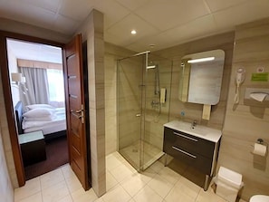 A hotel bathroom with a glass-enclosed shower, a sink, and a toilet.