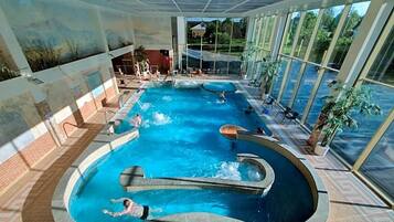 An indoor swimming pool with multiple lanes, surrounded by large windows.