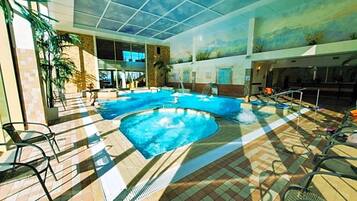An indoor swimming pool with a tiled floor, lounge chairs, and a mural on the ceiling.