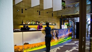 A reception area with a wooden counter, a digital display, and a staircase in the background. - Toila Spa Hotel (Toila)