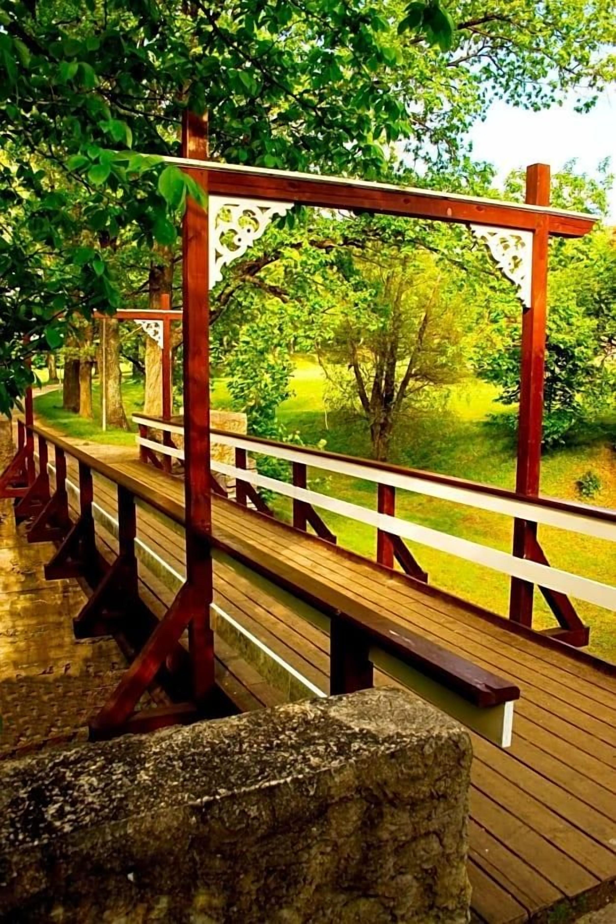 A wooden deck with benches and a pergola structure.