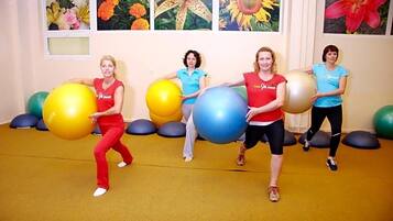Four individuals in a room with exercise balls, a yellow carpet, and floral wall art.