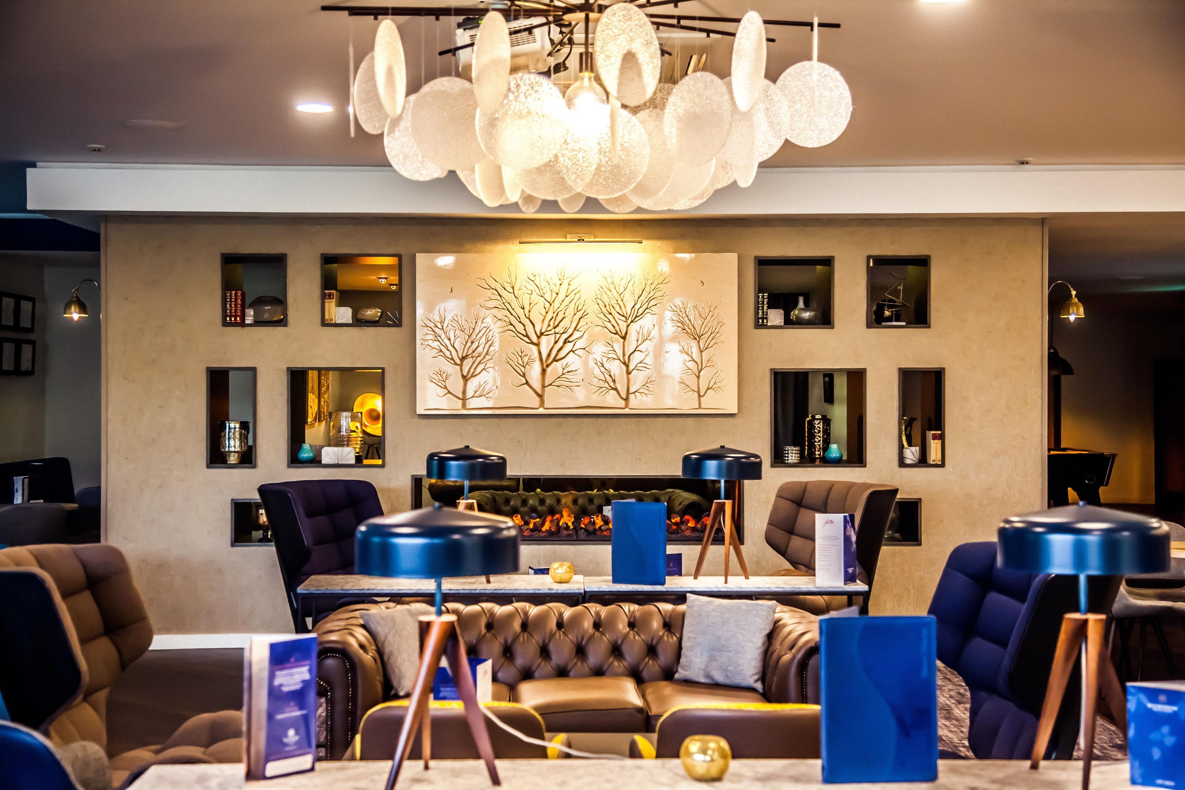 A modern lounge area with a fireplace, leather sofas, and a large abstract painting on the wall.