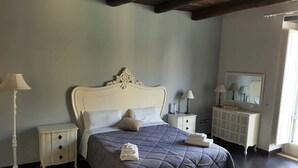 Een slaapkamer met een groot bed, twee nachtkastjes, een dressoir en een spiegel.