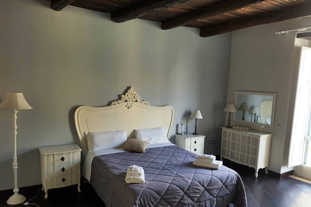 Une chambre à coucher avec un grand lit, deux tables de chevet, une commode, une coiffeuse et un miroir.