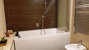 Een moderne badkamer met een badkuip, een wastafel en een douche.
