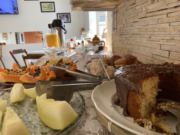 A buffet table with various food items including a chocolate cake, papaya slices, and other desserts.