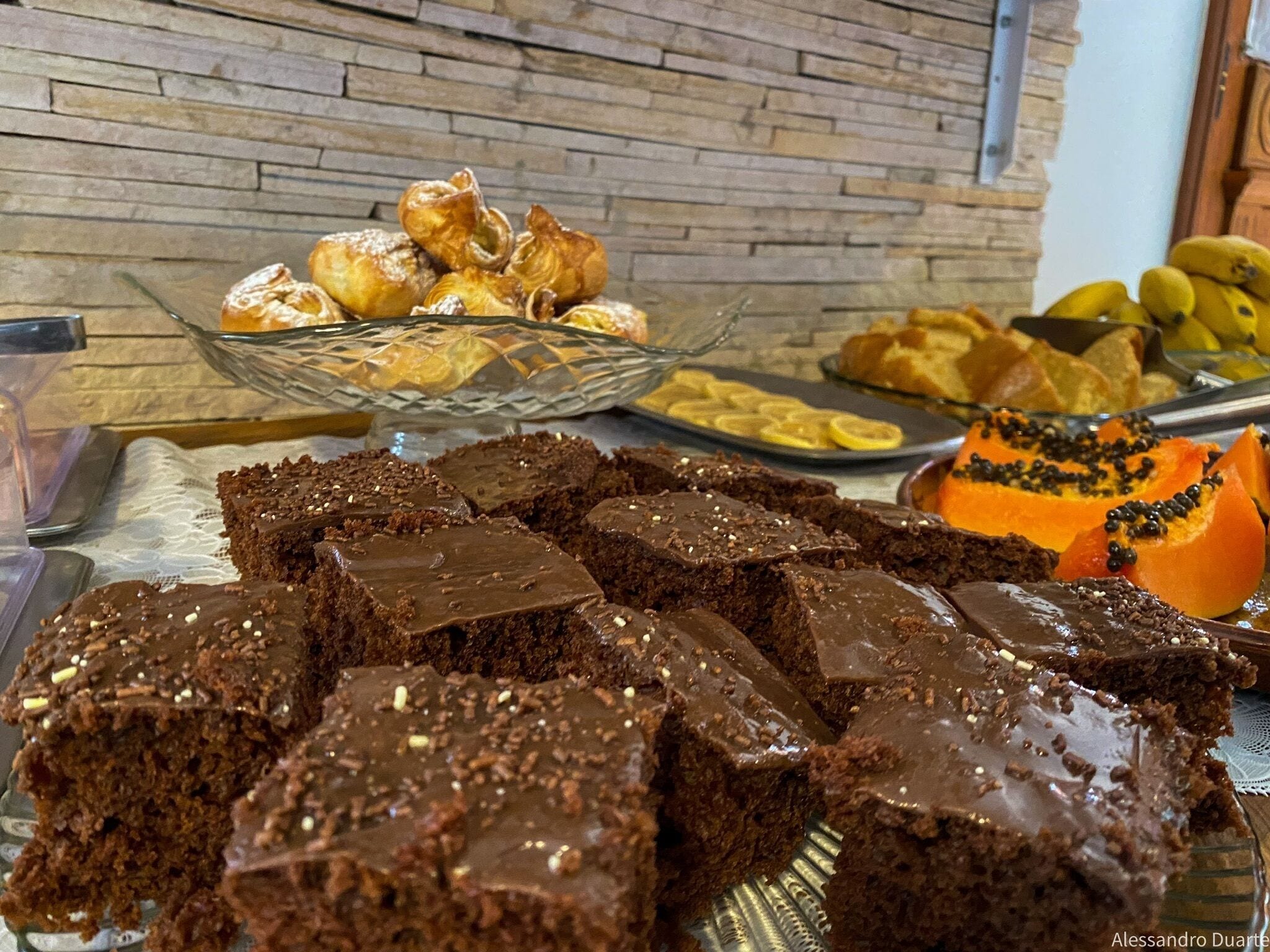 A buffet with various desserts including brownies, pastries, and a papaya topped with black seeds.