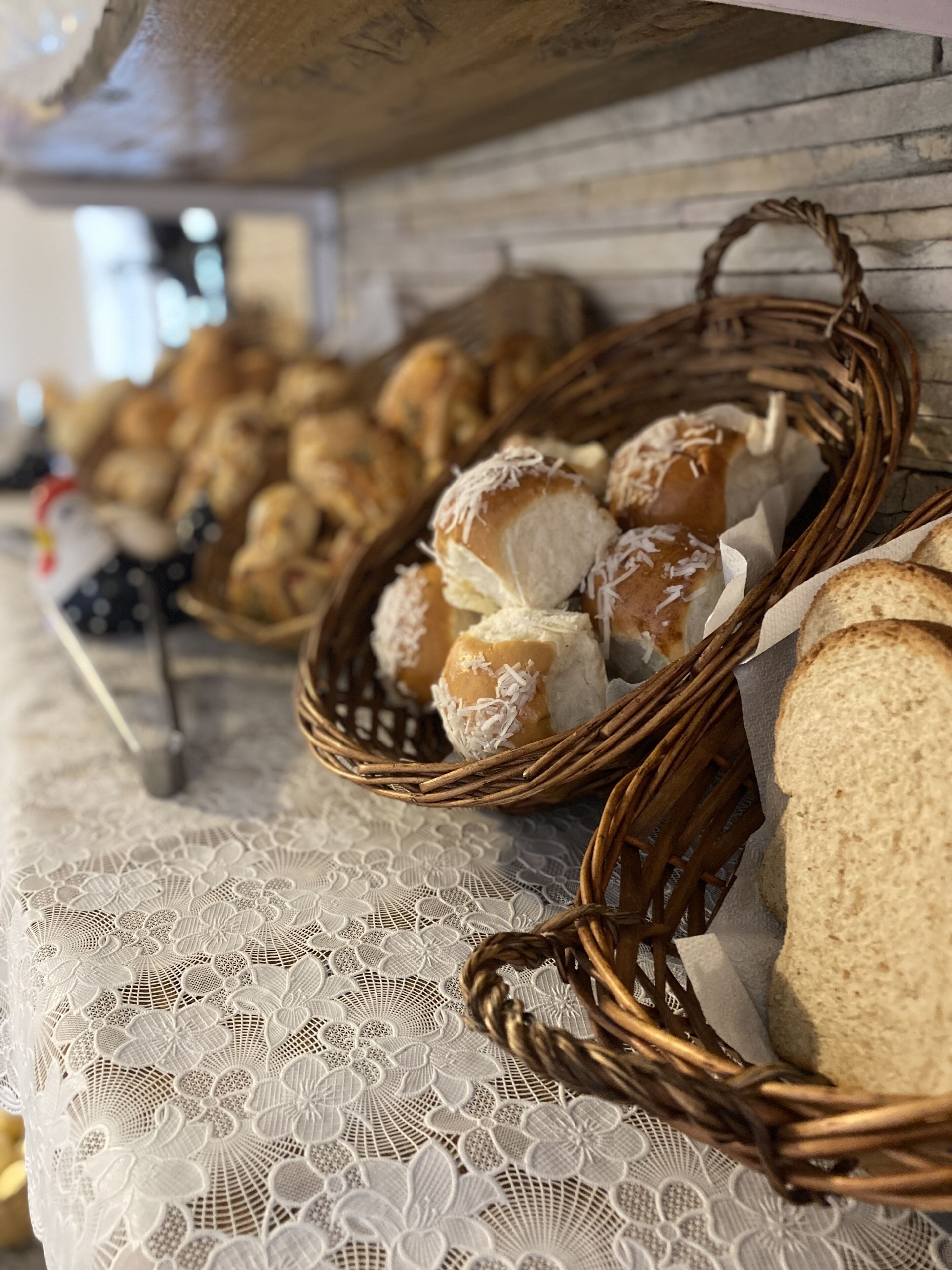 Un tavolo con cestini di pane e dolci, una tovaglia in pizzo e un cesto di vimini.