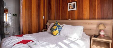 A wooden-paneled room with a bed, a nightstand, and a wall-mounted picture.