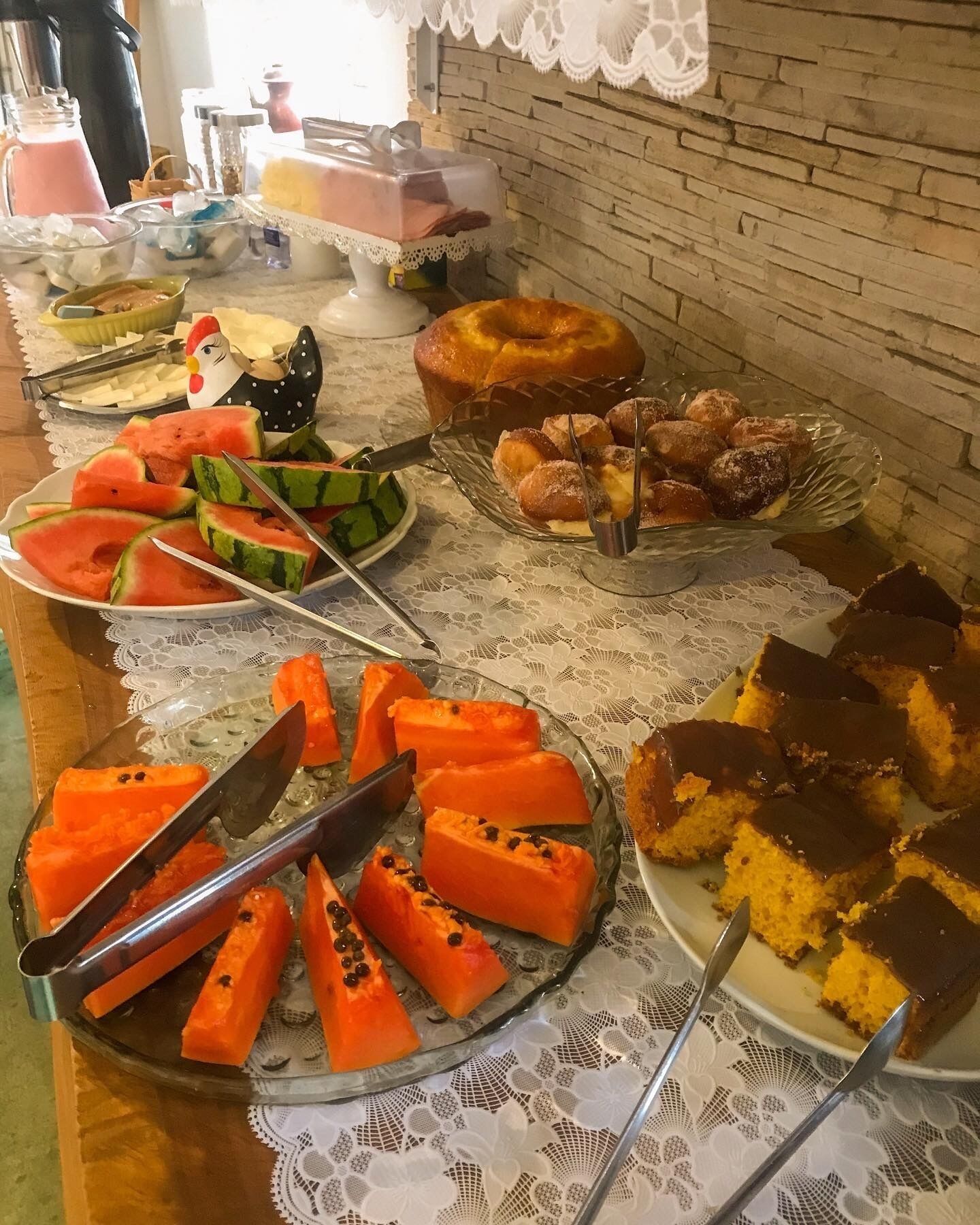 A buffet table with various dishes including watermelon, pastries, and a cake.