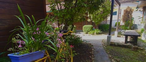 A yellow bicycle with a blue basket and potted plants parked in a garden area.