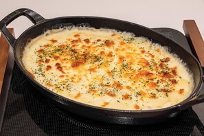 En støbejernsgryde med en cremet ret, måske en gratin, på en komfur.