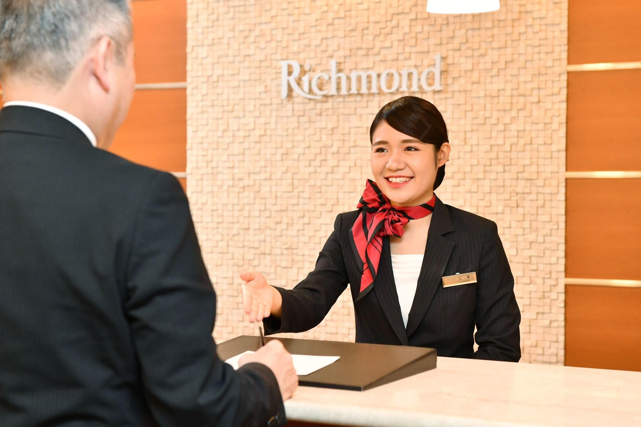 A hotel reception desk with a receptionist and a guest.