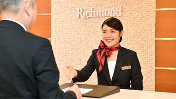 A hotel reception desk with a receptionist and a guest.