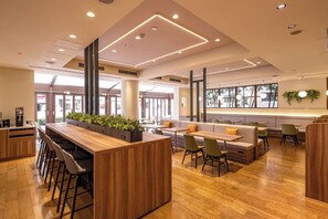 En moderne restaurant med en træbar, siddepladser og store vinduer.