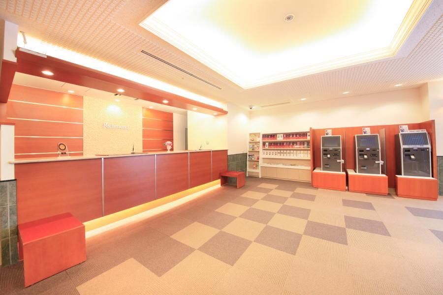 A reception area with a check-in counter, a small seating area, and self-service kiosks.