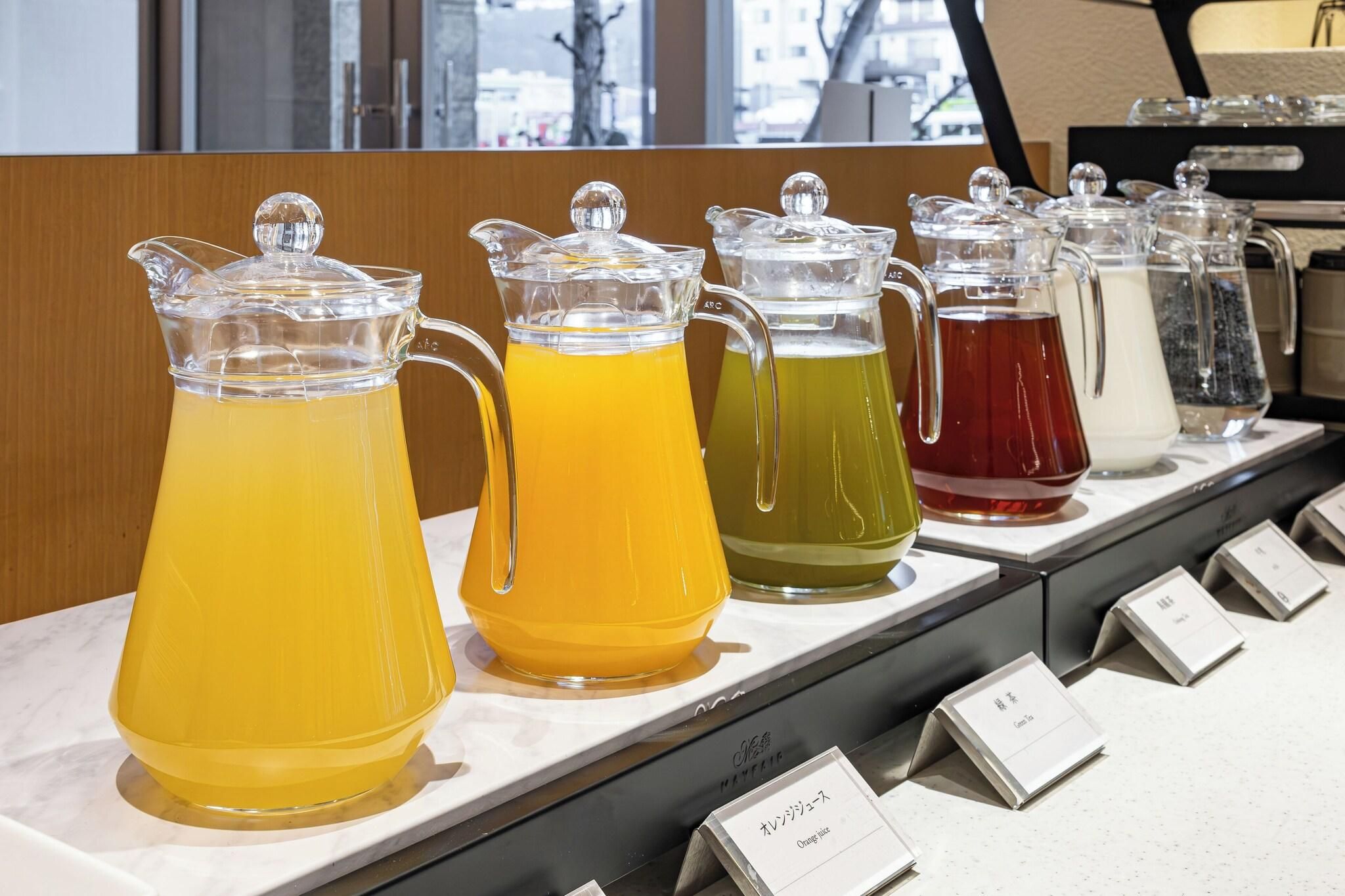 A beverage station with pitchers of different colored drinks, each with a label.