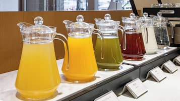 A beverage station with pitchers of different colored drinks, each with a label.
