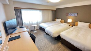 Habitación de hotel con dos camas, un escritorio con una computadora portátil, un televisor y una mesita redonda.