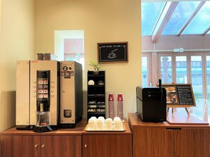 L'intérieur d'un café, avec une machine à café, un tableau affichant le menu et une fenêtre donnant sur le paysage.